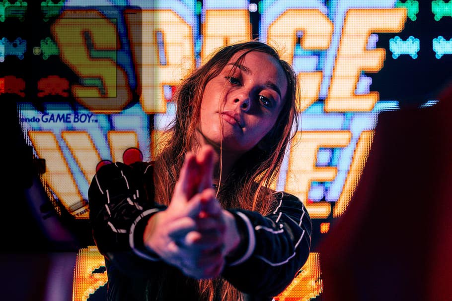 girl pointing hands with space invaders and nintendo game boy on the background