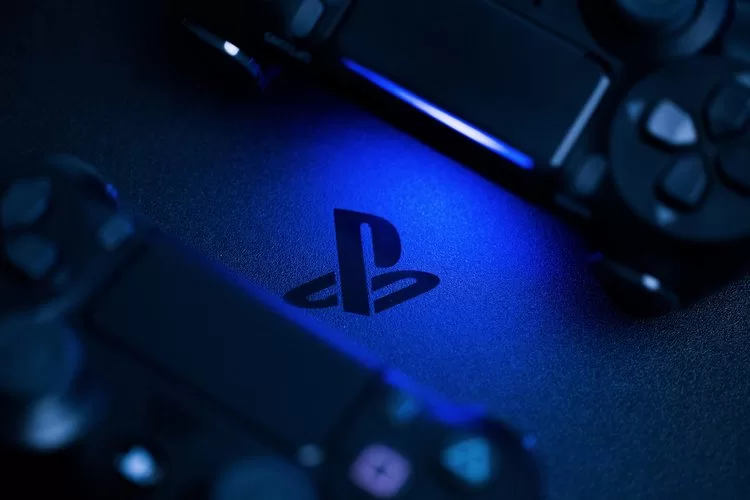 playstation logo in dark background with two black controllers